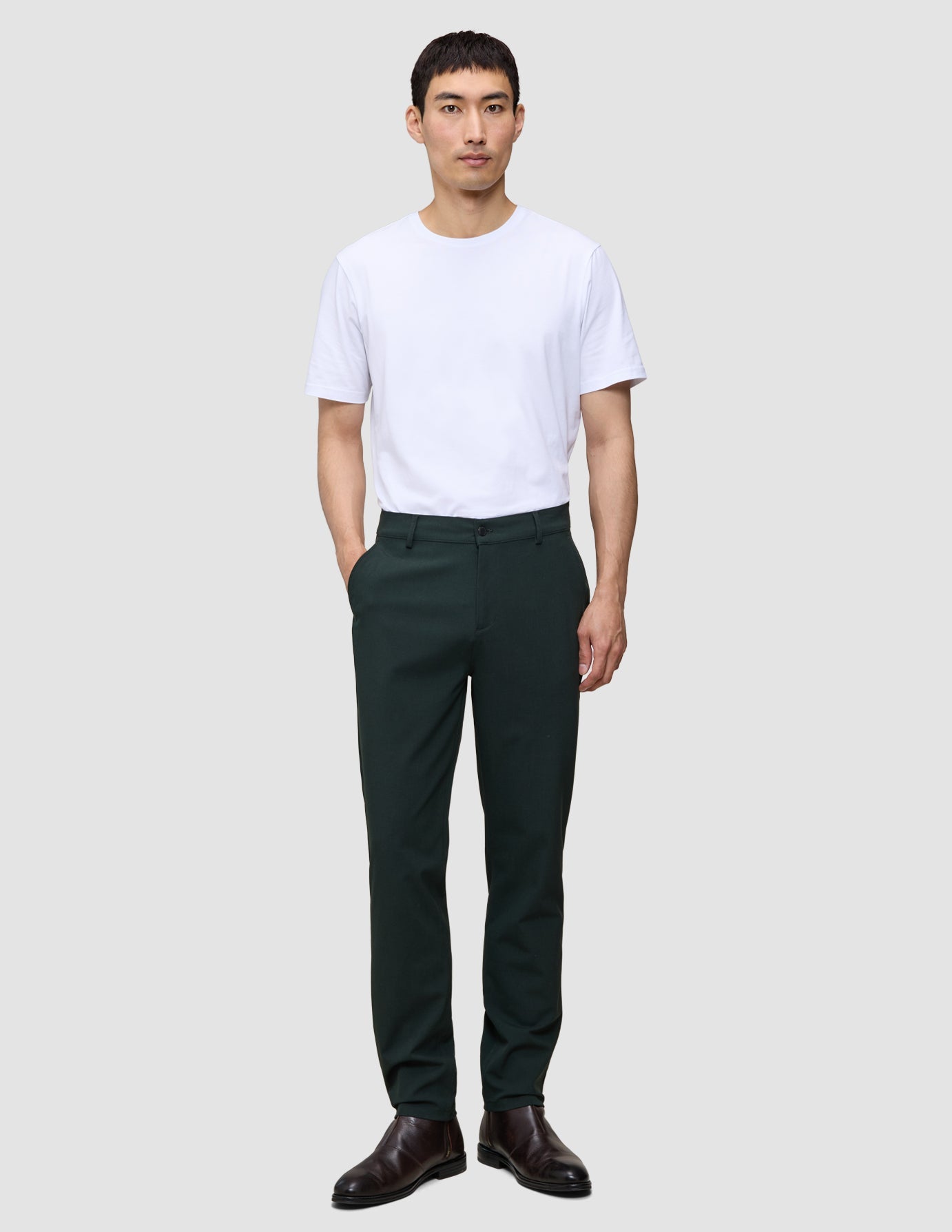En man i en vit t-shirt och Ease Pants Regular Northern Pine står vänd framåt.
